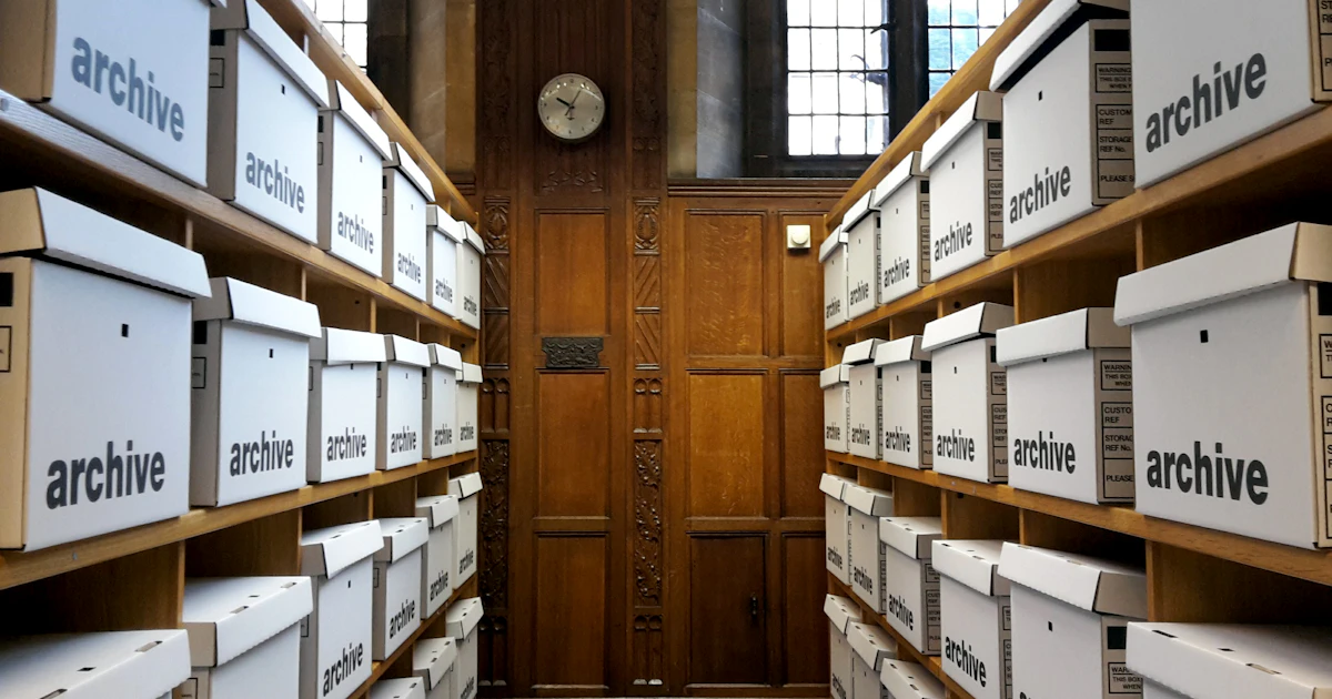 archiveと書かれた保管箱が両側の棚に並ぶ書庫の通路
